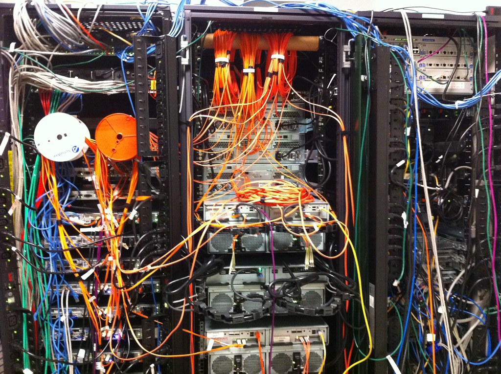 Rack de servidores com cabos de rede, representando infraestrutura de data warehouse e data lake