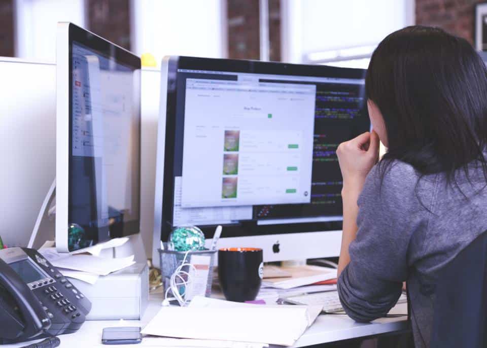 Profissional monitorando painéis de custo e desempenho de cloud em múltiplas telas