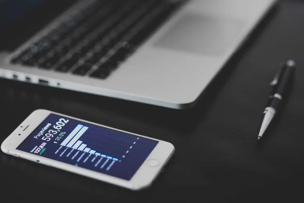 Profissional analisando dados de Power BI em laptop e celular