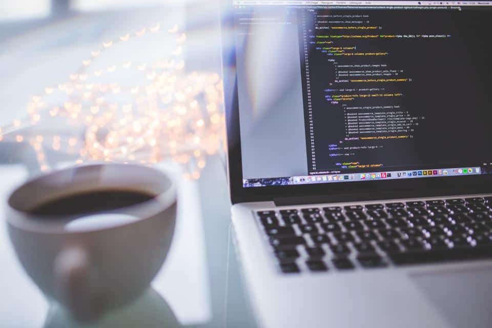 Código de pipeline de dados sendo editado em laptop, xícara de café ao lado