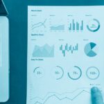 Mão segurando relatório com gráficos de dashboard ao lado de notebook, representando erros comuns em dashboards de Power BI