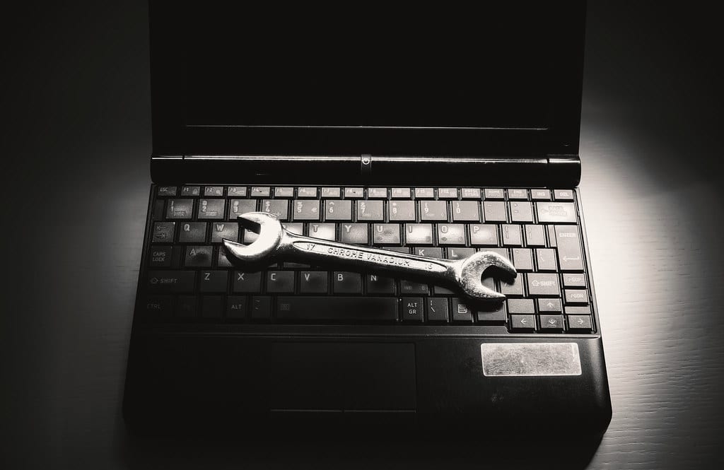 Chave inglesa sobre teclado de notebook, simbolizando manutenção e suporte de outsourcing de TI